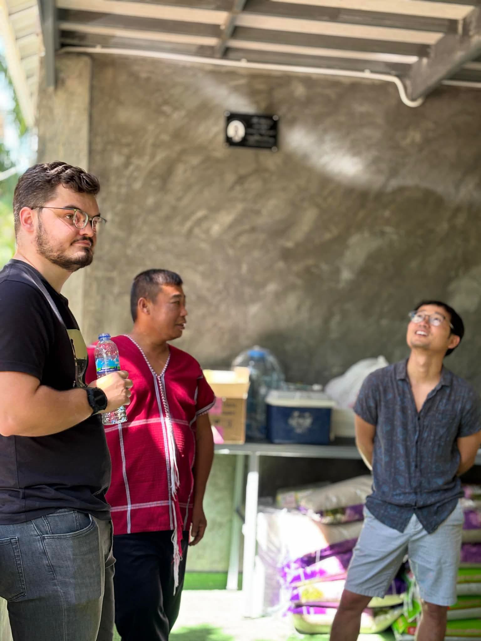 Gio, Samson and Dr. Mowae standing together with rice bags stacked behind them
